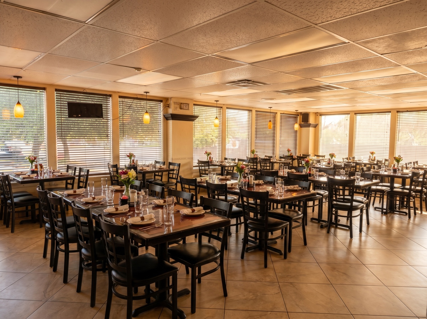 Comedor cálido con mesas servidas y flores frescas